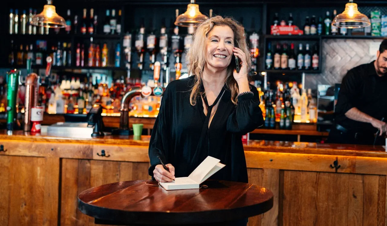 Woman running a pub taking a telephone call